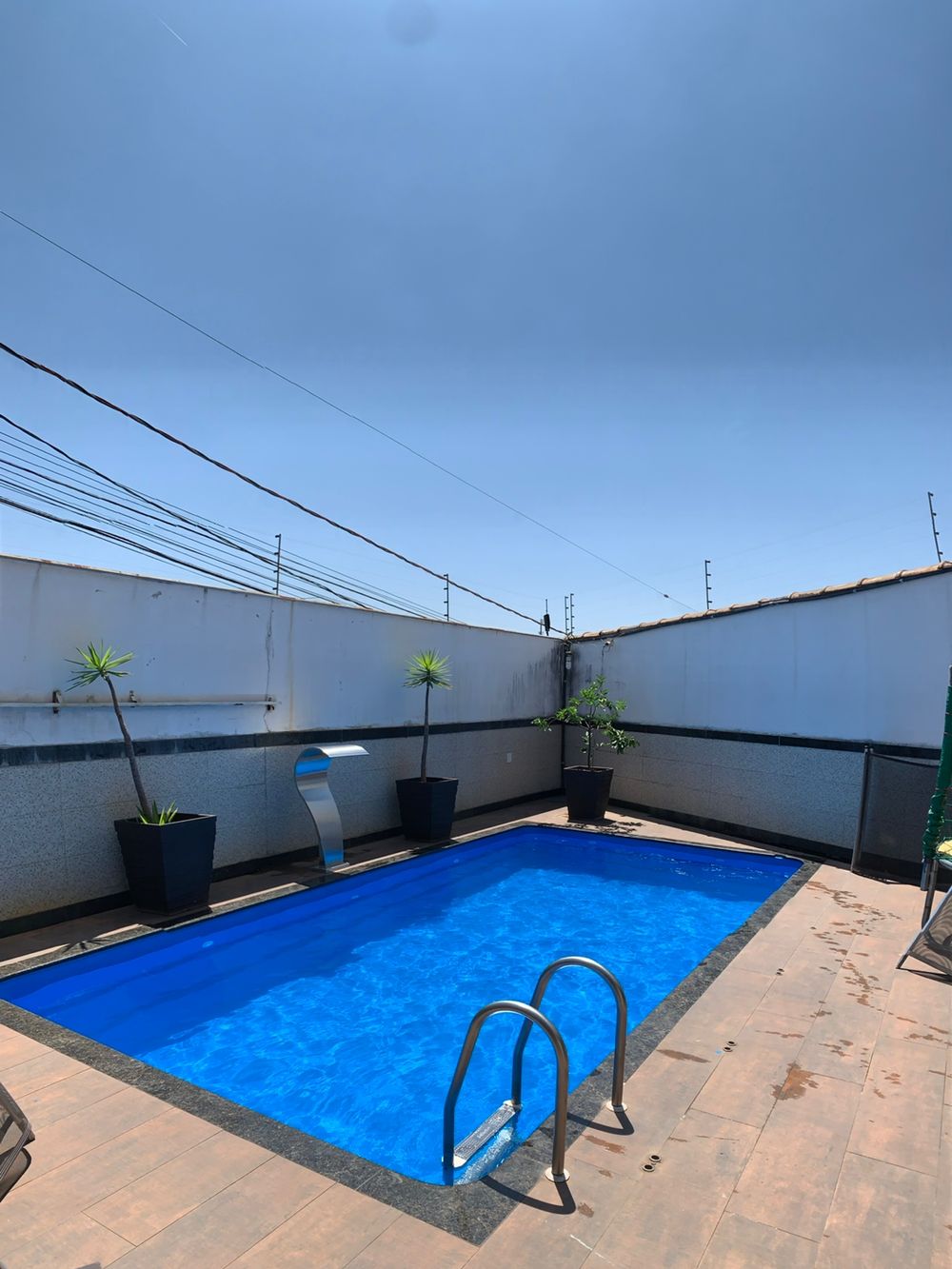 Piscina depois da reforma, azul, cheia e com cascata